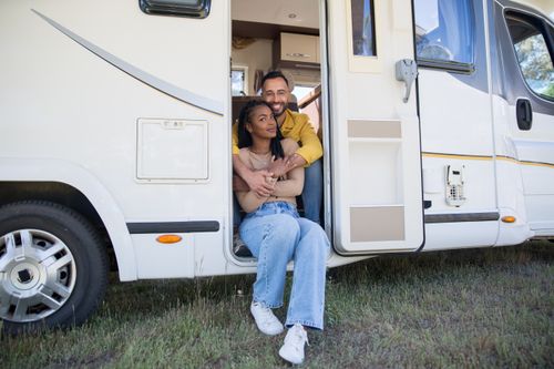 Free Smiling interracial couple sitting in a campervan enjoying their vacation in Portugal. Stock Photo