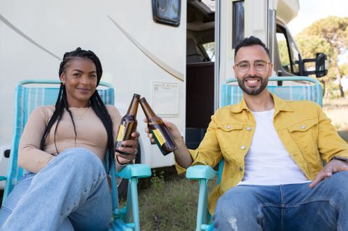 Free Joyful couple enjoying beer while camping by their camper van in Portugal. Stock Photo