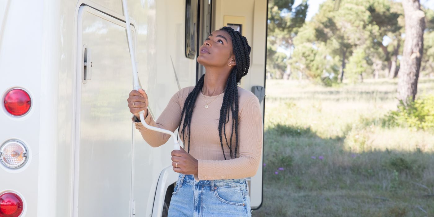 A woman adjusting the arm of an RV awning