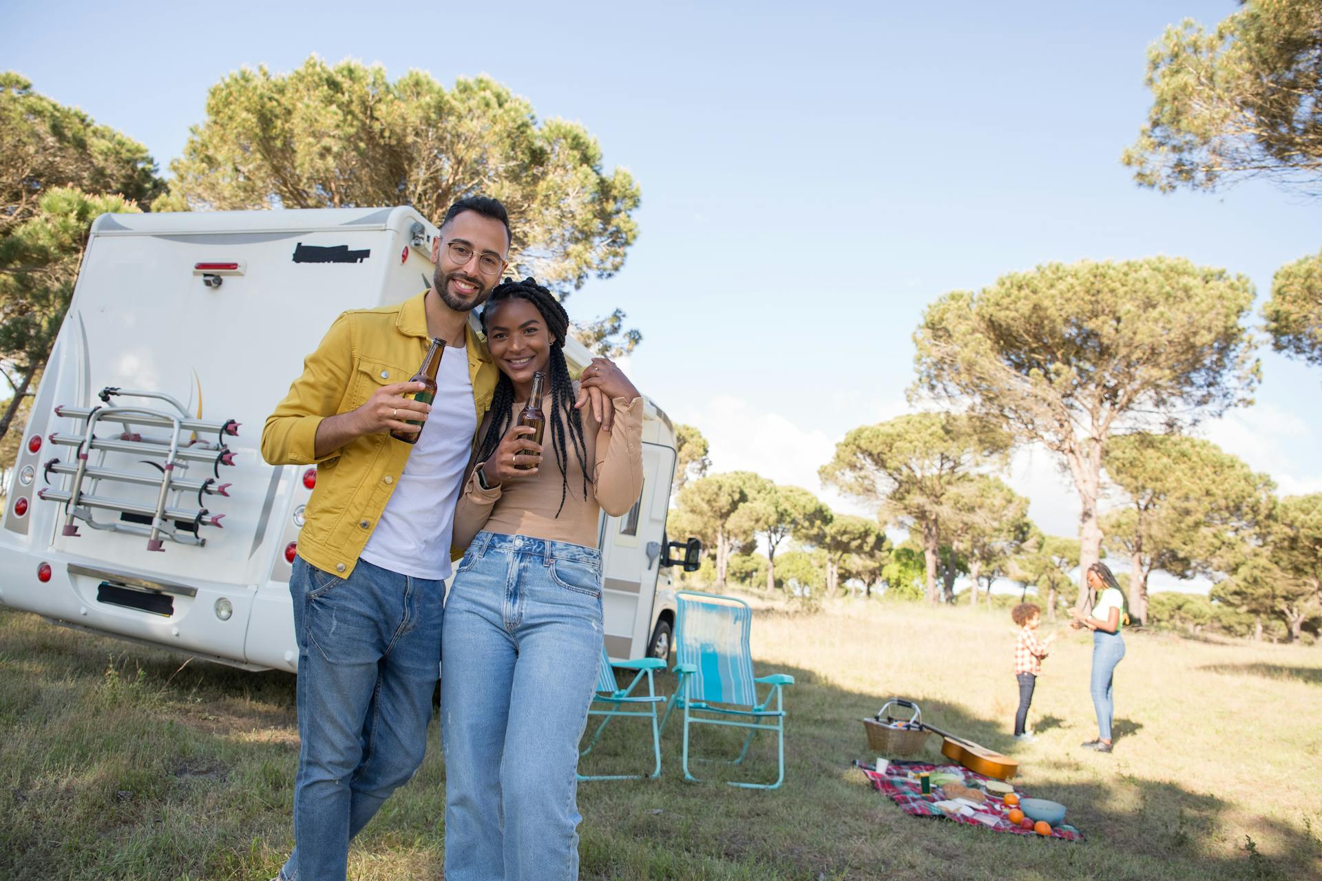 A cheerful couple stands next to their RV in a scenic outdoor setting in Portugal.