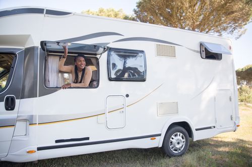 Free A woman smiles from a motorhome window during a sunny road trip in Portugal. Stock Photo