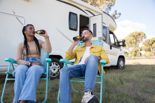 Free Couple sitting in front of campervan drinking, enjoying outdoor leisure time in Portugal. Stock Photo