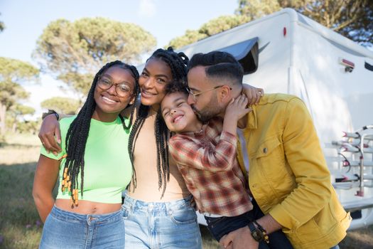 A joyful family bonding outdoors near a caravan on a sunny day in Portugal.