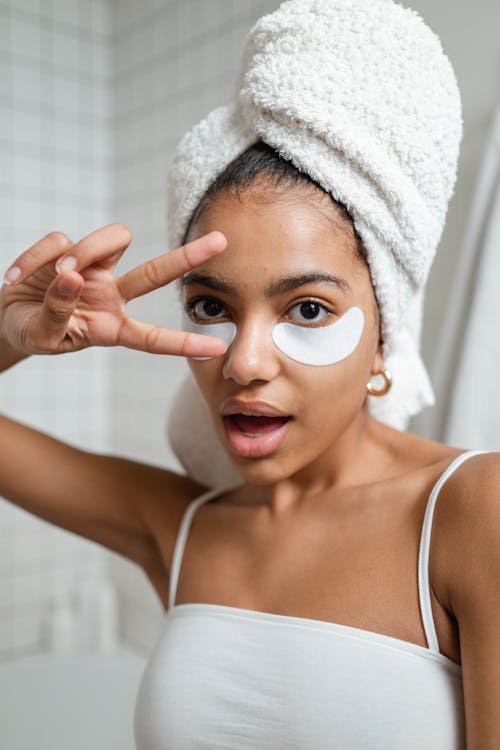 Free Woman With Under Eye Masks Doing A Peace Sign Stock Photo