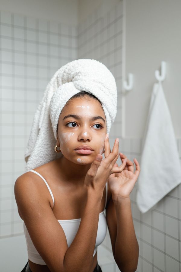 Woman with a towel wrap applying Oakmoss face cream