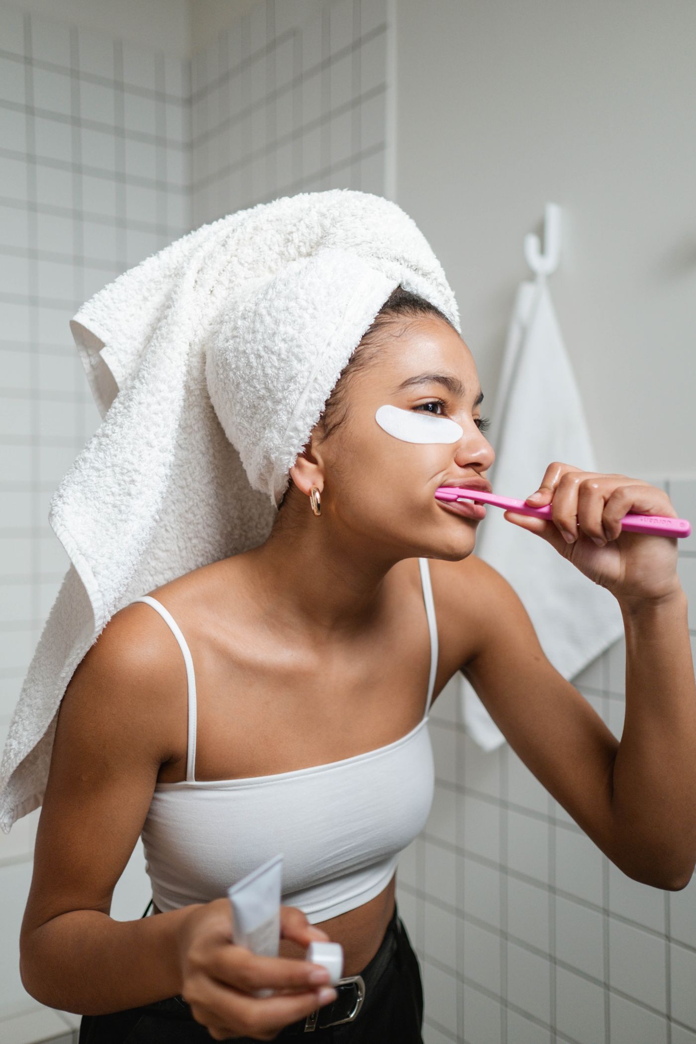 Woman brushing her teeth with a manual toothbrush during a bright bathroom self care routine
