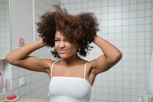 Smiling woman with afro hairstyle enjoying a moment of self-care in her bathroom.