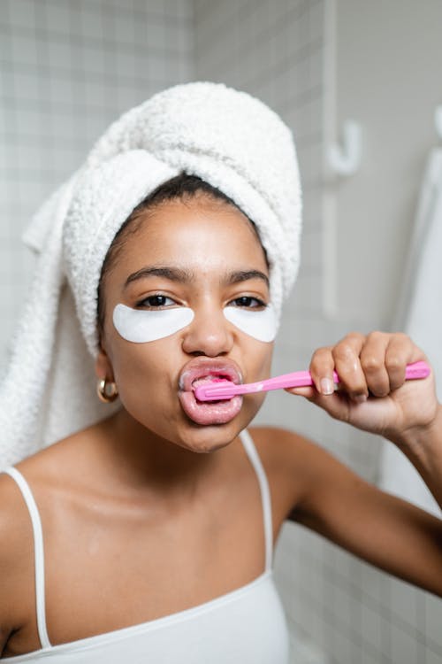 Woman Brushing Her Teeth With White Bath Towel On Head