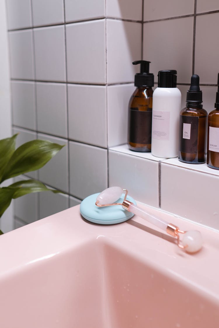 Brown And White Plastic Bottles On Pink Ceramic Sink