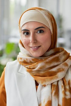 Portrait of a smiling woman wearing a stylish hijab in an office setting.