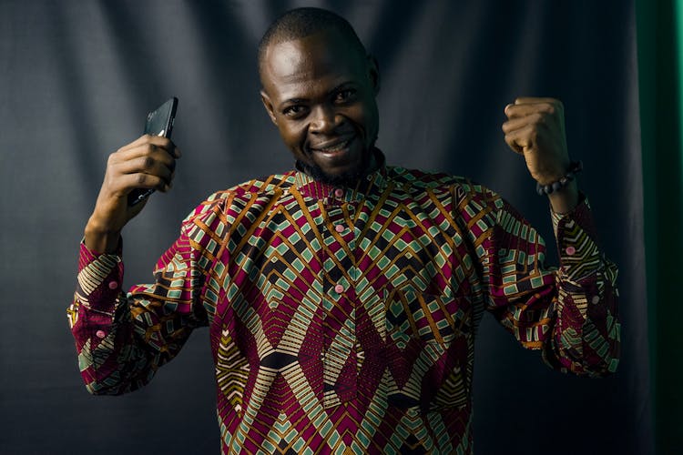 Man In Geometric Print Shirt Holding Black Smartphone