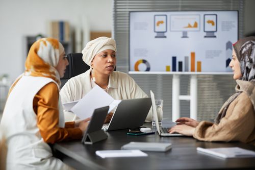 Free Three diverse women in headscarves engaged in a business meeting at a modern office with charts. Stock Photo