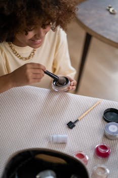 Happy woman with afro hair applying makeup in a relaxed indoor setting.