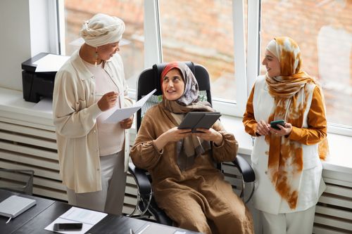 Free Three Muslim women in hijabs engaged in a business meeting, fostering teamwork. Stock Photo