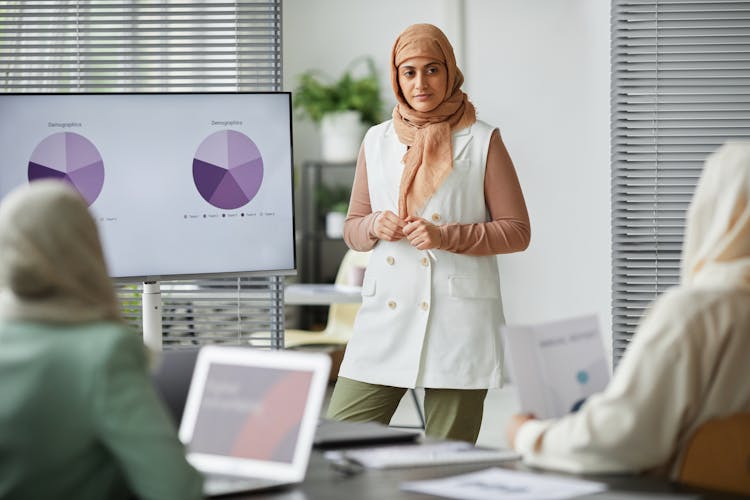 A Woman Standing In Front Of Her Colleagues