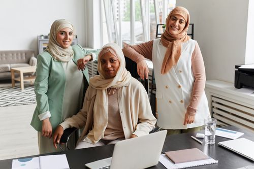 Free Three Muslim businesswomen in hijabs collaborating in a modern office setting. Stock Photo