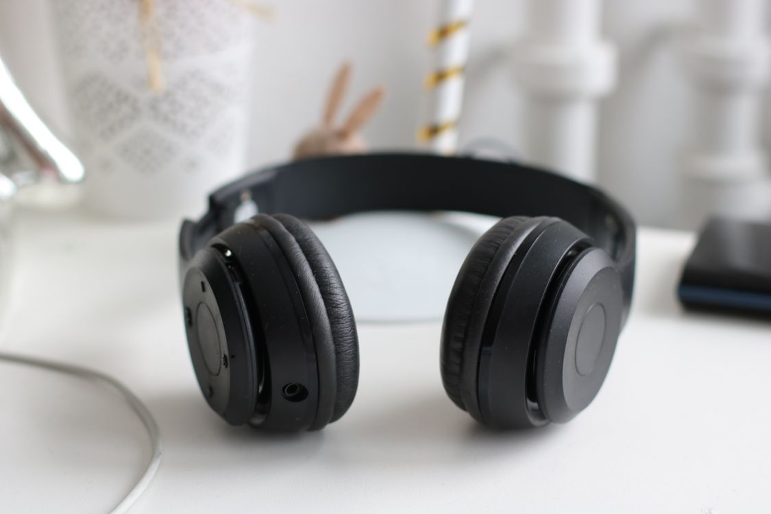 Black cordless headphones resting on a white desk.