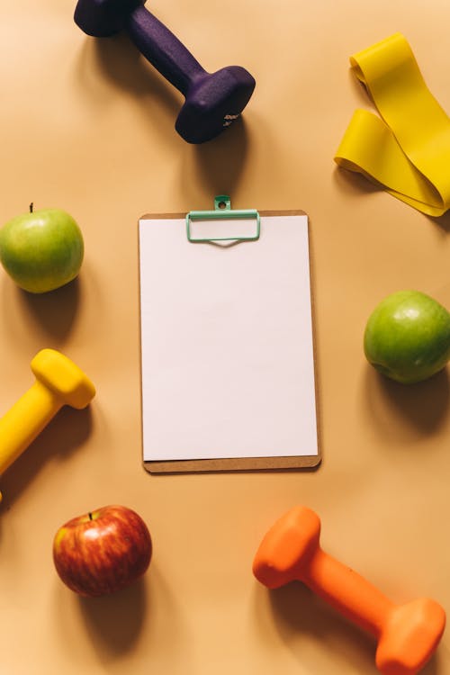 Overhead Shot of Dumbbells, Apples and a Clipboard