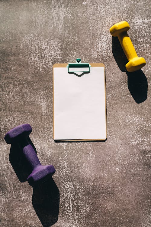 Overhead Shot of Dumbbells and a Clipboard