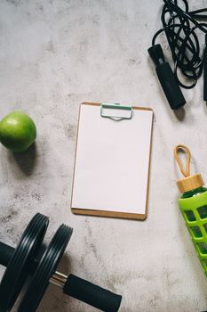 Overhead view of exercise equipment with a blank clipboard for fitness planning.