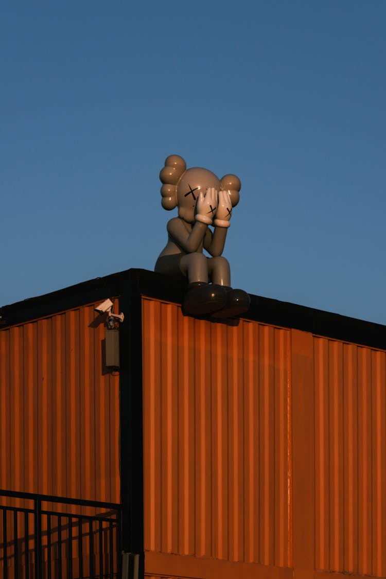 A Kaws Companion Sculpture Sitting On Top Of A Buiding