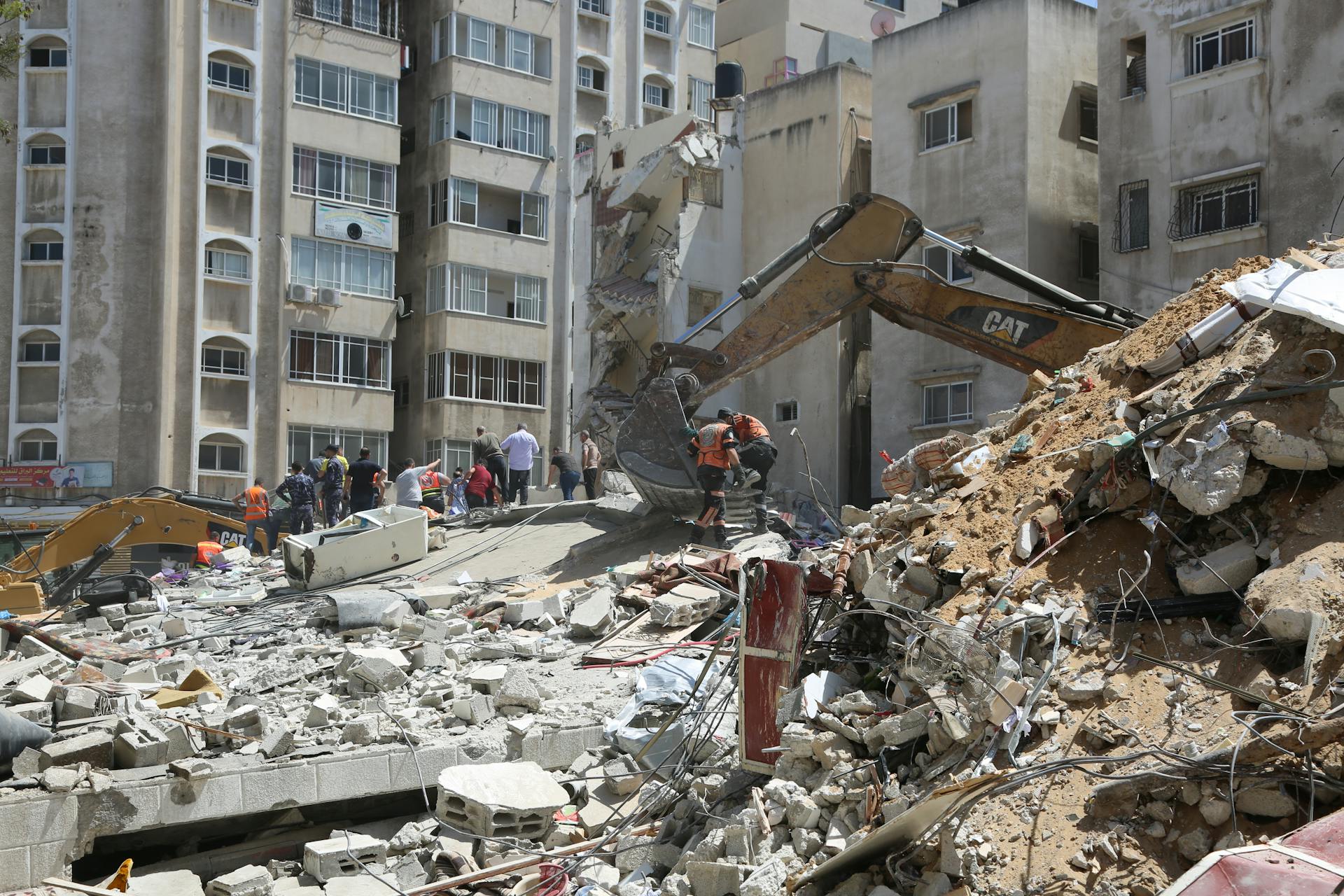 Heavy machinery demolishing urban buildings with workers clearing debris.
