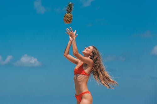 A Woman Tossing a Pineapple in Air
