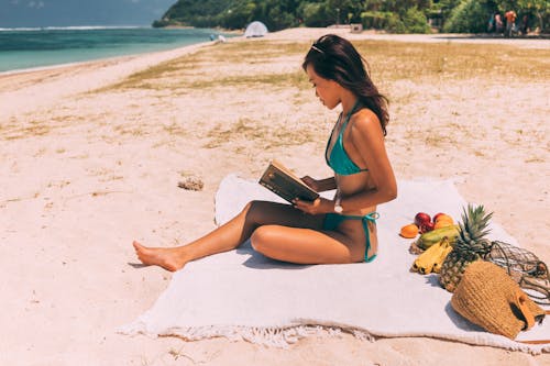 Free A Woman in Green Bikini Sitting on the Shore Stock Photo