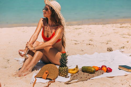 A Woman Sitting on the Beach over a Towel