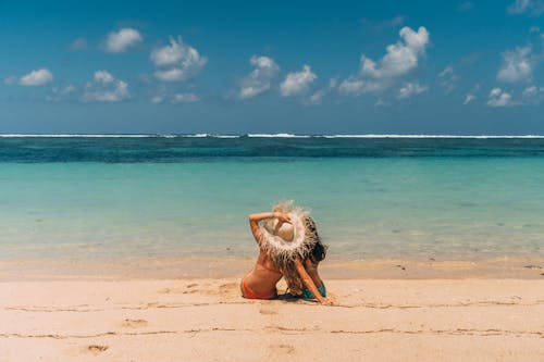 A Pair of Women in Bikinis Sitting on Beach Shore Watching the Waves