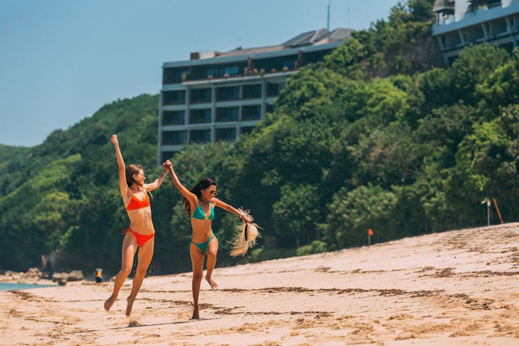 A Pair Of Women In Bikinis Enjoying The Beach