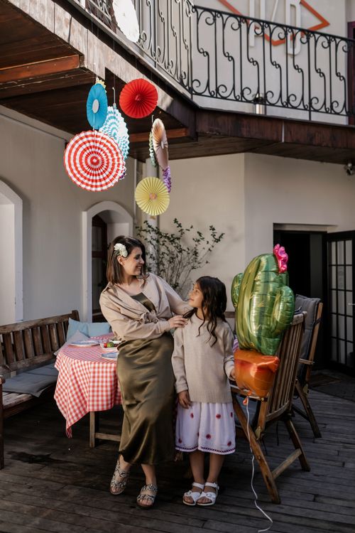 Free A mother and daughter enjoy a festive party outdoors, surrounded by colorful decor and balloons. Stock Photo