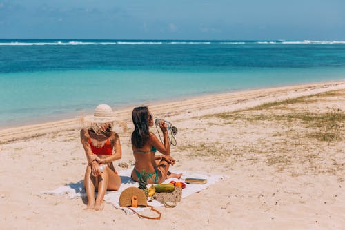 Free Women in Their Bikini Sitting on the Beach Stock Photo