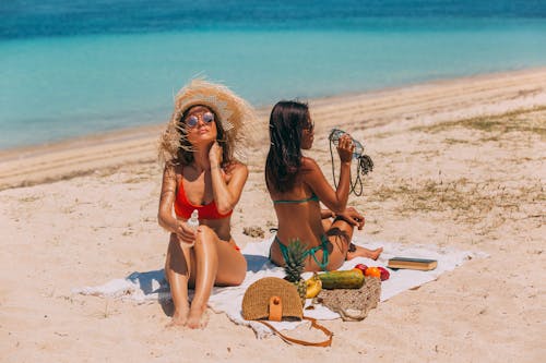 Two Women in Bikini Sitting on Beach Shore