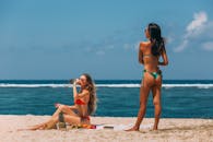 两名女子在阳光明媚的海滩上放松身心，欣赏海景