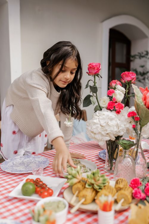Free A Hispanic girl reaches for food on a decorated table, celebrating Cinco de Mayo. Stock Photo