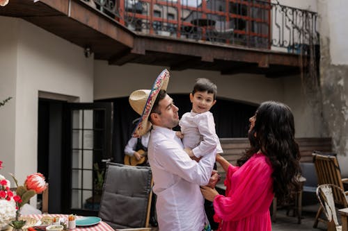 Man in White Long Sleeve Shirt Carrying His Son