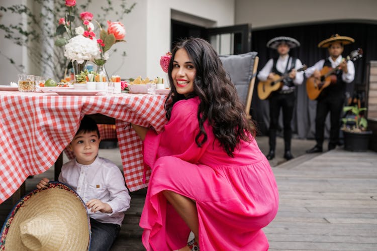 A Woman In Pink Dress Finding The Boy Hiding Under The Table