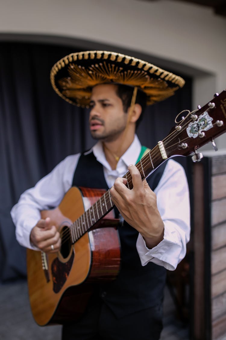 Man In White Dress Shirt With Sombrero Playing An Acoustic Guitar