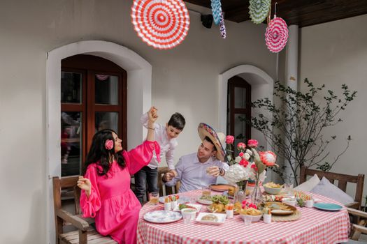 A joyful family enjoying a meal with Mexican decor and vibrant outfits.