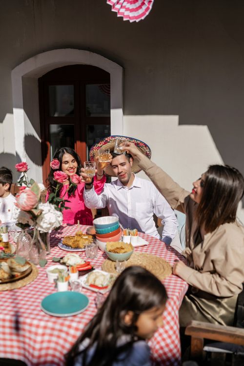 Free Group of adults enjoying a festive meal outdoors, toasting at a Mexican celebration. Stock Photo