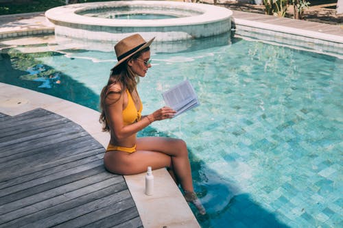Free A Woman Sitting in the Poolside Reading a Book Stock Photo