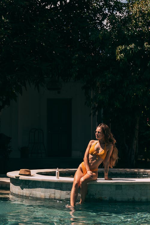 A Woman in Yellow Bikini Sitting on the Kiddie Poolside