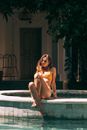 A Woman in Yellow Bikini Sitting on the Poolside