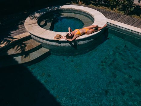 A Woman in Bikini Sunbathing on the Poolside