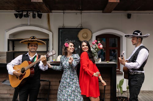 Men in Sombreros Playing Guitars and Women in Dresses Standing between them