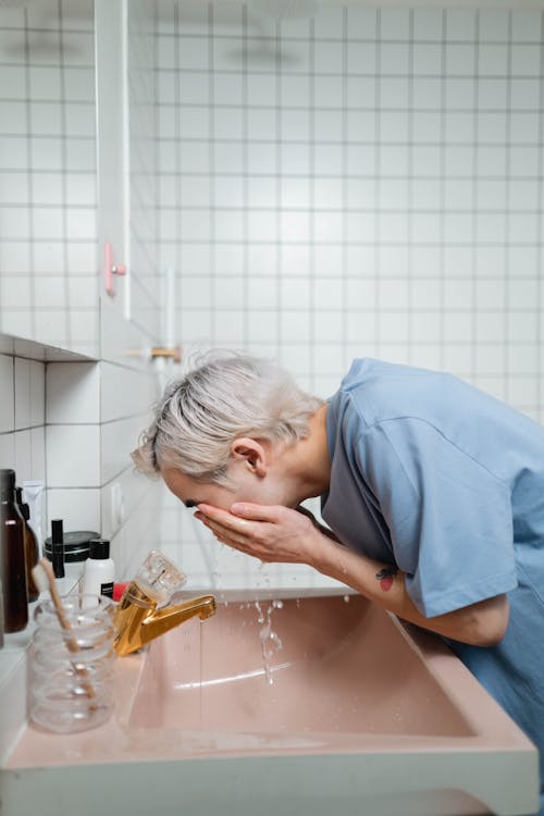 Man in Blue T-shirt Washing His Face