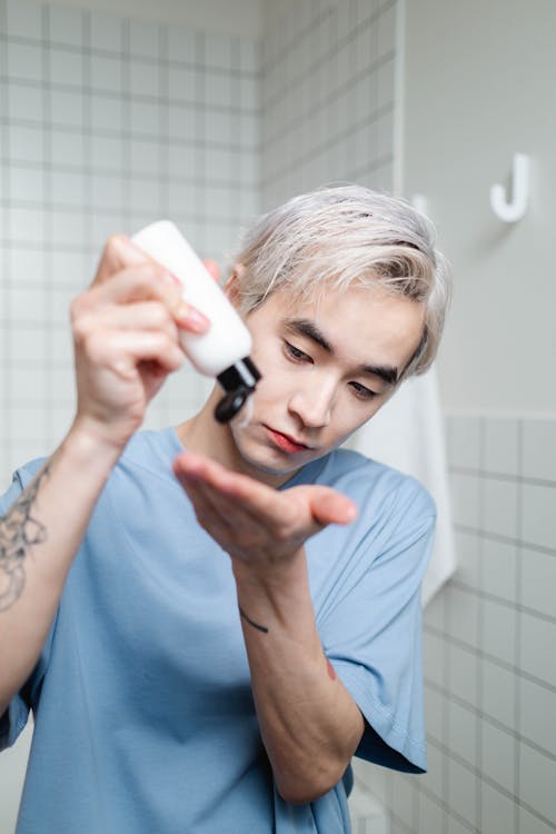 Free Man in Blue Crew Neck Shirt Holding A Bottle Of Beauty Product Stock Photo