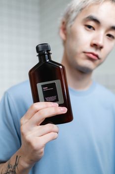 Man in Blue Crew Neck Shirt Holding A Brown Bottle