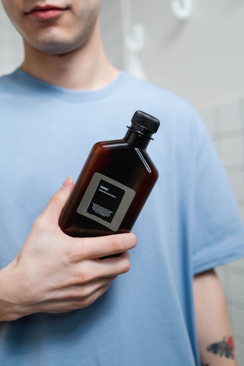 Free Man in Blue Crew Neck Shirt Holding Brown Bottle Stock Photo